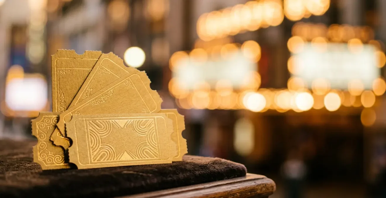 Close-up of theater tickets and glowing marquee lights with natural depth of field