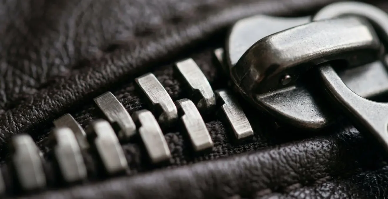 Extreme close-up macro photograph of luxury metal zipper teeth and pull hardware showing craftsmanship details